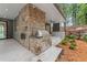 Outdoor kitchen and fireplace with stone work on the covered patio and a landscaped yard at 1171 Lupo Loop, Chattahoochee Hills, GA 30268