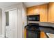 Kitchen featuring wood cabinetry, black appliances, and a washer/dryer in a closet at 195 14Th Ne St # 1404, Atlanta, GA 30309