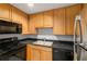 Galley kitchen features light wood cabinetry, black appliances, and a double basin sink at 195 14Th Ne St # 1404, Atlanta, GA 30309