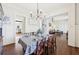 Dining room open to the kitchen and living room with hardwood floors, wainscoting and a chandelier at 3530 Horizon Ct, Cumming, GA 30041