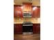 Close up of kitchen showcasing a stainless steel oven, microwave, and cherry wood cabinets at 85 Providence Pkwy, Covington, GA 30014