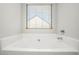 Relaxing bathroom showcasing a deep soaking tub with fixtures and a window view at 71 Pulaski Ave, Hampton, GA 30228