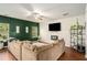 Cozy living room with a large sectional sofa, mounted TV, and bright windows complemented by vibrant indoor plants at 71 Pulaski Ave, Hampton, GA 30228