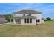 Expansive backyard view of a two-story home, featuring a covered patio and lush lawn at 165 Haverling Pass, Hampton, GA 30228