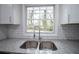 Close up of a stainless steel, double basin kitchen sink with granite countertops and subway tile backsplash at 3893 Bonnie Se Ln, Atlanta, GA 30354