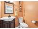 Cozy powder room with toilet, vanity, framed mirror, and decorative accents at 2118 Township Dr, Woodstock, GA 30189