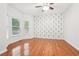Spacious bedroom featuring hardwood flooring, neutral walls, a ceiling fan, and bright, sun-filled windows at 2118 Township Dr, Woodstock, GA 30189