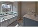 Bathroom with tiled tub, updated vanity, modern fixtures, and natural light from the window at 2234 Oak Falls Ln, Buford, GA 30519