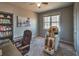 A carpeted bedroom with two chairs, a desk, a bookcase, and a view of the backyard through the window at 2234 Oak Falls Ln, Buford, GA 30519