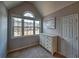 A neutral colored bedroom with a large window, a white dresser and a door that leads to the hallway at 2234 Oak Falls Ln, Buford, GA 30519