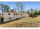 Backyard view with a brick house, sloped lawn, and natural landscaping at 3844 Rena Se Ln, Smyrna, GA 30082