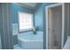 Bright bathroom featuring a corner tub with tile surround, floral accents, and blue striped wallpaper at 4288 Wyndham Park Cir, Decatur, GA 30034