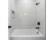 Modern bathroom features a sleek white tub with black fixtures and stylish marble-like tiled walls at 7180 Whitfield Dr, Riverdale, GA 30296