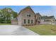 Expansive brick home featuring an attached three-car garage and manicured lawn at 177 Haverling Pass, Hampton, GA 30228