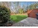 Backyard features a grassy lawn, brick wall, and wooded surroundings at 185 Willow Stream Ct, Roswell, GA 30076