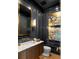 Stylish powder room featuring sleek dark walls, elegant gold accents and a marble vanity countertop at 1131 Lupo Loop, Chattahoochee Hills, GA 30268