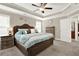 Bright main bedroom featuring a queen bed, tray ceiling, fan, and carpet at 117 Cottage Nw Walk, Cartersville, GA 30121