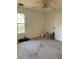 Empty bedroom with a ceiling fan, window letting in natural light, and bare walls and worn carpeting at 470 Yearling Dr, Loganville, GA 30052