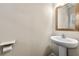 Compact powder room features a pedestal sink, framed mirror, and convenient toilet paper holder at 2474 Norwood Park Xing, Atlanta, GA 30340