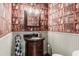 Powder room featuring wallpaper with bookshelf pattern and ornate wood vanity with dark countertop at 5980 Mallet Ct, Cumming, GA 30040