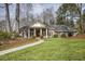 Charming brick home featuring a manicured lawn, mature trees, and a covered entrance at 11765 Mountain Laurel Dr, Roswell, GA 30075