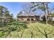 A view of the backyard with green grass, trees, and the back of a brick single story home at 1949 Capri Dr, Decatur, GA 30032