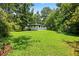 Expansive backyard with lush green grass, mature trees, and a charming white house in a serene setting at 2403 Dawn Dr, Decatur, GA 30032