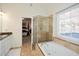 Bright bathroom featuring a glass-enclosed shower and a soaking tub beneath a window at 305 Collegiate Dr, Powder Springs, GA 30127