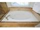 Close up of soaking tub with tile surround and fixtures beneath a window at 305 Collegiate Dr, Powder Springs, GA 30127