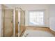 Bright bathroom featuring a glass-enclosed shower and a soaking tub beneath a window at 305 Collegiate Dr, Powder Springs, GA 30127
