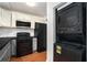 Compact kitchen featuring essential appliances and modern cabinetry with a stacked washer/dryer unit at 6962 Oakhill Cir, Austell, GA 30168