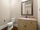 Cozy powder room featuring a vanity with granite countertop, framed mirror, and classic fixtures at 2845 Echols Rd, Cumming, GA 30041