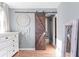 View of bedroom featuring wooden sliding barn door, hardwood flooring, and dream catcher at 368 Triumph Se Cir, Atlanta, GA 30354