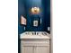 Stylish bathroom with a round mirror, modern vanity, and blue painted walls at 240 Mado Ln, Chattahoochee Hills, GA 30268