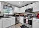 Well-lit kitchen featuring white cabinets, stainless steel appliances, modern fixtures, and tile backsplash at 3000 Storybook Ln, Grayson, GA 30017