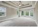 Spacious bedroom with tray ceilings, ceiling fan, neutral carpet, and large windows at 627 Warsaw Rd, Roswell, GA 30075