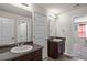 Well-lit bathroom featuring double sinks, a dark vanity, a large mirror, and a view into an adjoining bedroom at 15 Mary Jane Ln, Covington, GA 30016