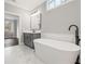 Bright bathroom with a modern freestanding tub, gray cabinets, and marble-look flooring at 837 Lakemont Dr, Canton, GA 30114