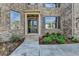 Elegant entryway featuring a black front door with sidelights, brick steps, and landscaped garden beds at 5533 Addison Woods Pl, Buford, GA 30518