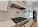 Close-up of the kitchen area with professional-grade gas range and quartz countertops at 5533 Addison Woods Pl, Buford, GA 30518
