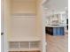 Mudroom with bench and storage that opens to kitchen with navy island and pendant lights at 5533 Addison Woods Pl, Buford, GA 30518