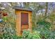 Enclosed outbuilding with wooden door surrounded by mature bushes and trees at 5642 N Highway 212, Covington, GA 30016