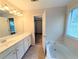 Bright bathroom featuring a double sink vanity and a soaking tub beneath a window at 11780 Wellsley Way, Alpharetta, GA 30005