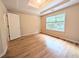 Bedroom with hardwood floors, a large window, and a tray ceiling with recessed lighting at 11780 Wellsley Way, Alpharetta, GA 30005