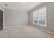 Bright, carpeted bedroom with a large window offering natural light and neutral paint at 4776 Trilogy Park Trl, Hoschton, GA 30548
