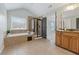 Well-lit main bathroom with a soaking tub, glass shower, and wooden vanity with granite countertop at 4776 Trilogy Park Trl, Hoschton, GA 30548