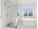 Bright bathroom featuring glass shower, large soaking tub, and a large window for natural light at 2849 Parkridge Ne Dr, Brookhaven, GA 30319