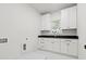 Bright laundry room features white cabinets, black countertops, and tiled floor at 2849 Parkridge Ne Dr, Brookhaven, GA 30319