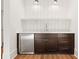 Close-up of a stylish wet bar featuring dark wood cabinets, a stainless steel mini-fridge, and modern lighting at 2849 Parkridge Ne Dr, Brookhaven, GA 30319