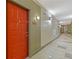 Condo hallway with an orange entry door and neutral decor, illuminated with mounted sconce lighting at 400 17Th Nw St # 2025, Atlanta, GA 30363